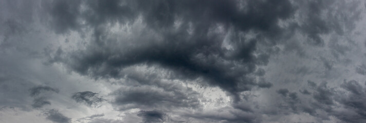 Obraz premium Panoramic background of gloomy grey cloudy sky with copy space for design. Heavy rainy clouds on gray sky. Concept background the sky is angry