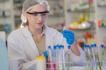 Scientists prepare for the experiment by wearing latex gloves. An experimenter arranges experimental equipment on a table with test tubes and chemicals for making drugs and biochemical for human.