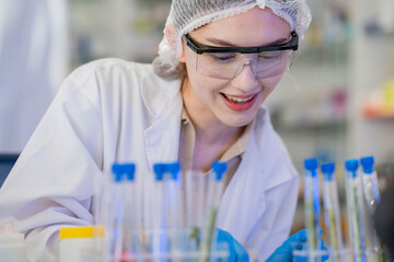 female scientist Experimenting through tubes of chemical liquids and plant samples. In a laboratory with test samples in the background in a modern laboratory By testing safely and cleanly.