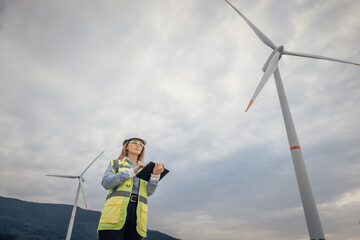 A female engineer inspects a wind turbine at a renewable energy facility, highlighting her key role...