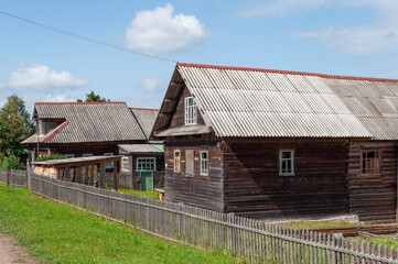 Old traditional country wooden houses in russian village, sunny summer morning