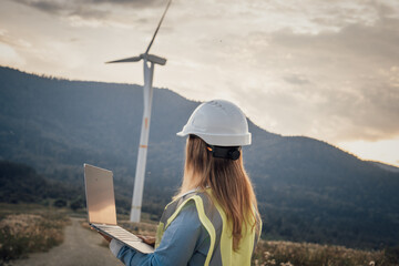 A skilled professional woman oversees a complex wind turbine operation on her laptop, surrounded by...