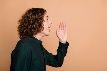Profile side photo of funny nice young man wear green stylish clothes look empty space announce news isolated on beige color background