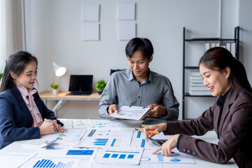 Asian business team analyzing financial data using calculator and laptop in office