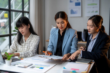 Three businesswomen discussing financial charts and data in modern office