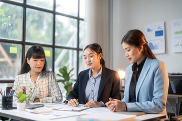 Three young businesswomen working together on a project, analyzing graphs and taking notes