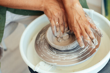 Fototapeta premium ceramics class, a man makes a clay plate on a potter's wheel