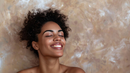 Obraz premium Portrait of a carefree laughing woman enjoying a spa treatment, bare shoulders, on a beige background