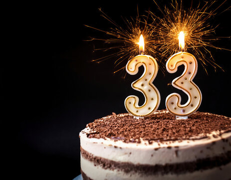Birthday cake with 33 years birthday candle on dark background with sparklers. copy space