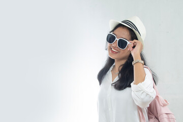 closeup, young Asian woman wearing straw hat, ping backpack and sunglasses while posing vacation is here, travel advertising studio shot isolated on white