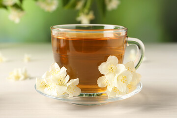 Hot jasmine tea in cup and flowers on white wooden table