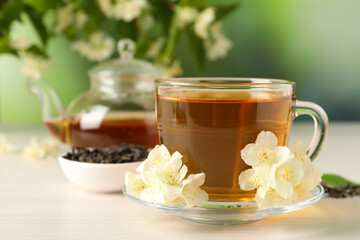 Hot jasmine tea in cup and flowers on white wooden table