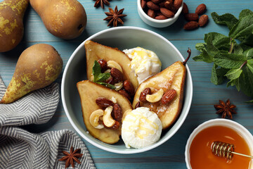 Delicious baked pears with nuts, ice cream and honey in bowl on light blue wooden table, flat lay