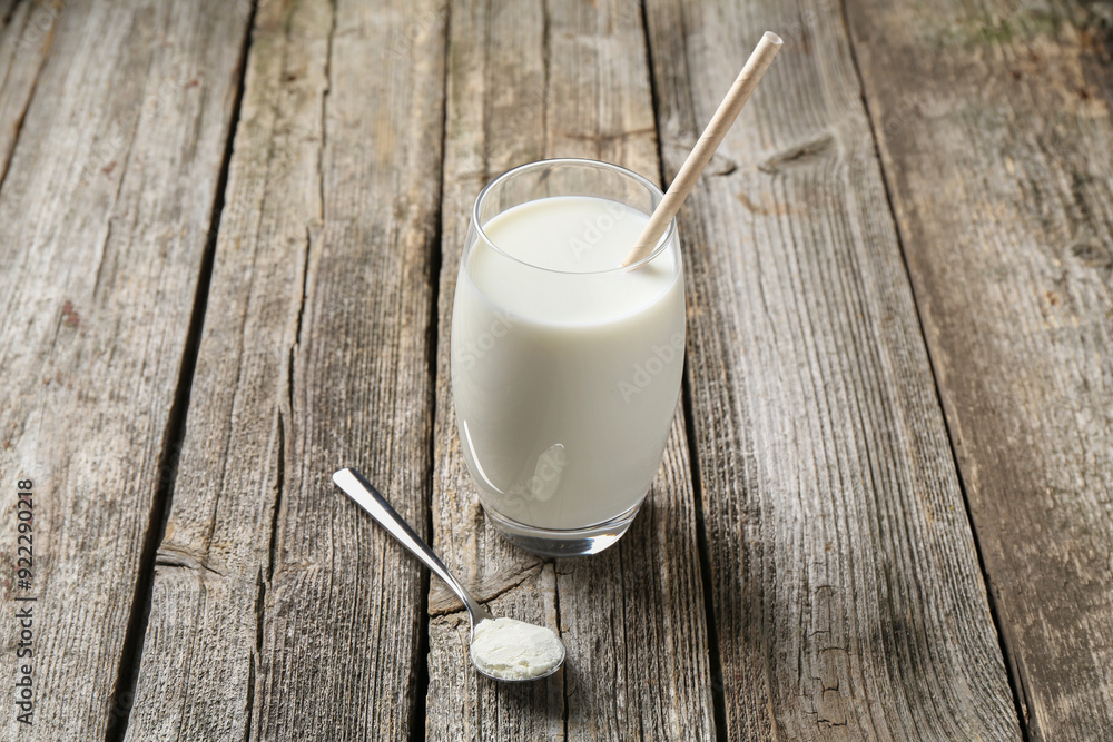 Poster Delicious protein shake in glass and spoon with powder on wooden table