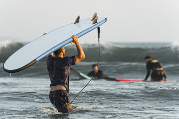 Group of friends getting into the water for surfing in Bali