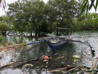 Obraz premium Wooden boat anchored along the forested river bank