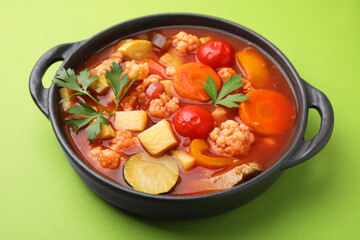 Tasty homemade stew with vegetables on light green table, closeup