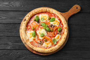 Delicious vegetarian pizza on black wooden table, top view