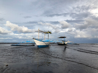 Beautiful view of a boat anchored by the sea on a bright, sunny, and cloudy day.