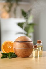 Essential oil diffuser, cosmetic products, mint and orange on wooden table at home