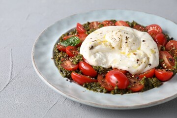 Fresh delicious burrata salad on light grey table, closeup
