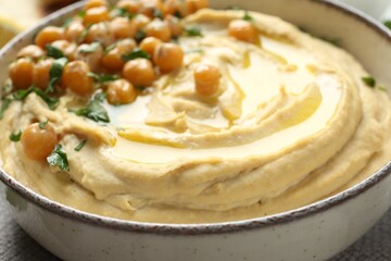 Delicious hummus with olive oil, chickpeas and parsley in bowl, closeup
