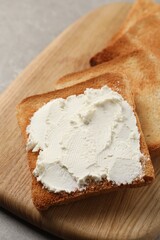 Delicious toasted bread slices with cream cheese on grey table, closeup