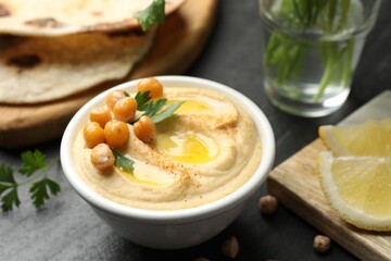 Delicious hummus with olive oil and chickpeas in bowl served on grey table, closeup