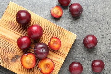Fresh plums on grey textured table, flat lay