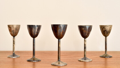 Antique weathered copper goblets with high stem on the brown wooden table. Close-up. Copy space. Selective focus.