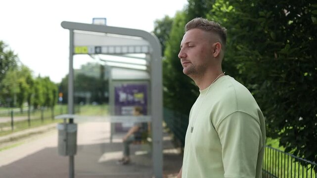 Tourist Caucasian man traveler with bag and suitcase sit at public transport bus station waiting with mobile smart phone 