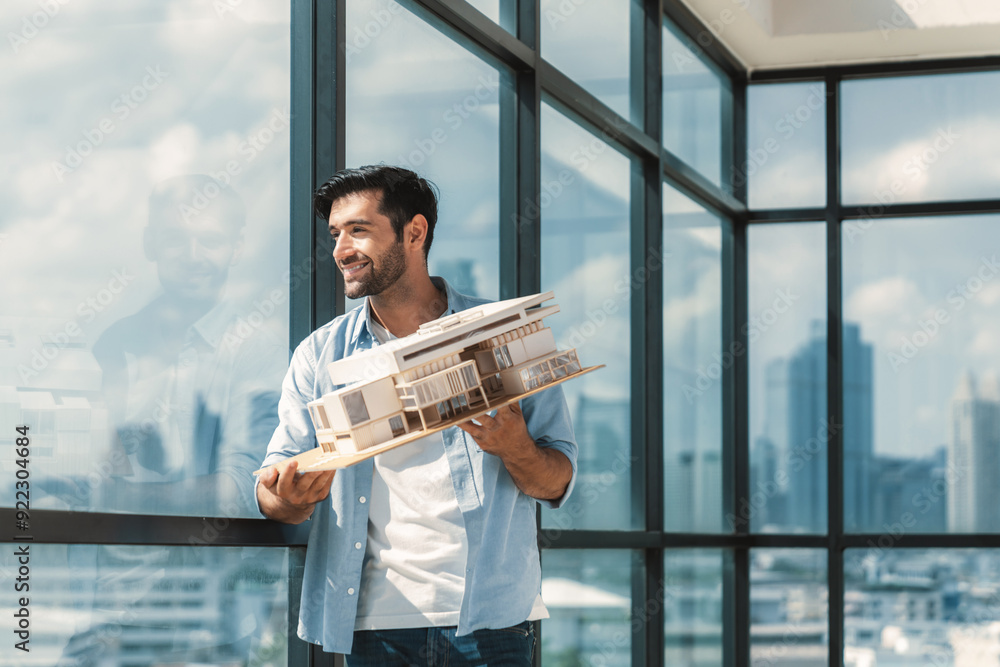 Poster handsome skilled architect engineer holds architectural model while inspect house model. professiona