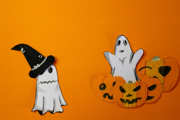 Funny ghost playing at scaring, coming out from behind pumpkins.Copy space