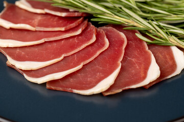 sliced ham with bacon on a board