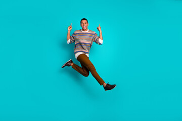 Full size photo of nice young man jump point fingers empty space wear sweater isolated on teal color background