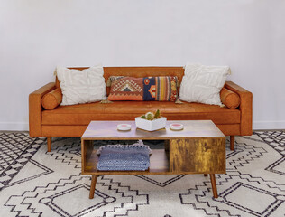 Living room with brown leather couch, coffee table, designer southwest rug. Wall for copy space.