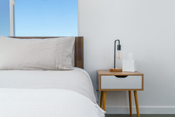 Modern bohemian desert home white bedroom with bed, side table, lamp