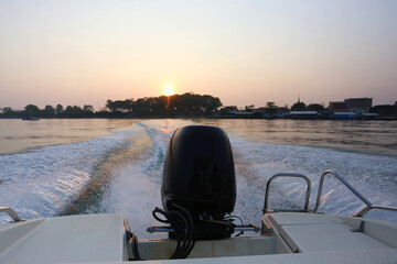 Rear view of a speedboat leaving the coast in the morning as the sunrise..