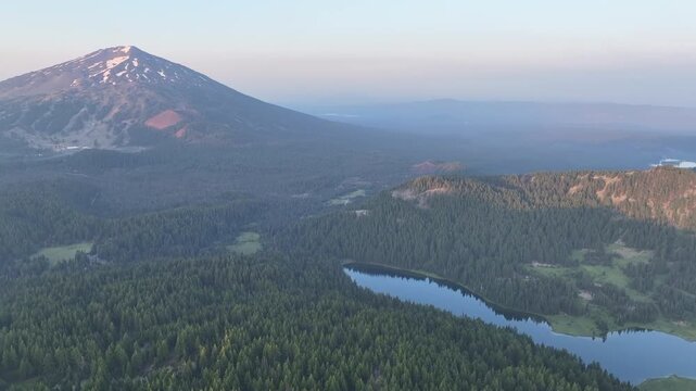 A serene sunrise illuminates Todd Lake and Mt. Bachelor, Oregon, during summer. This scenic mountain and its surrounding forests, near Bend, provide exceptional hiking, biking, climbing, and camping.