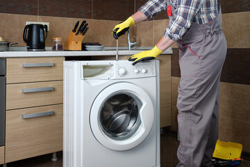 A service technician repairs a household washing machine.