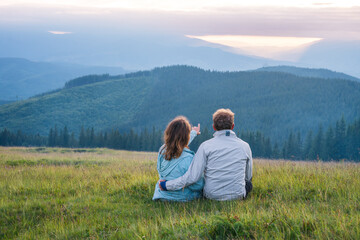 couple a man and a woman sit together bowing their heads on their shoulders and looking into the distance at a beautiful view relationships outdoor recreation dream travel family Carpathian Mountains