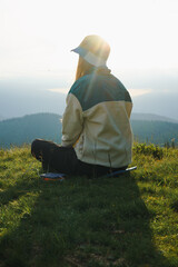 woman sit on a hill overlooking a mountain range, against the background of mountains, tourism, hiking, nature of the Carpathian, vacation, outdoor activities, meditation, poster, wallpaper 