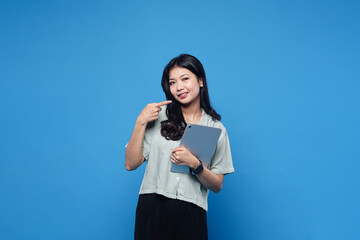 Excited korean woman with digital tablet, pointing at empty space, advertisement banner, holding gadget, showing promo offer, blue background.