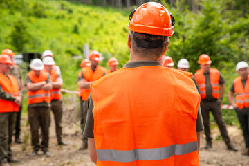 Builders in reflective vests, hardhats standing together at construction site. Group of builders in...