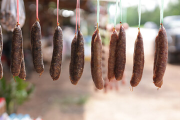 Meat sausages hung on a string at the market. Sausages hanging on strings outdoors.