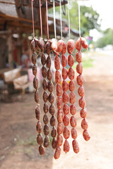 Sausages hanging in bunches outdoors with blurred background. Beef and pork sausages are displayed...