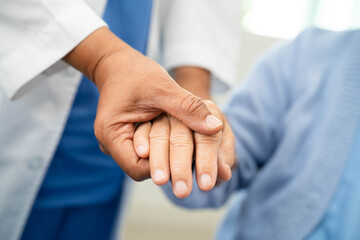 Doctor holding hand and help senior woman patient in hospital.