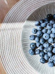 A lot of blueberries lie on the table in a plate