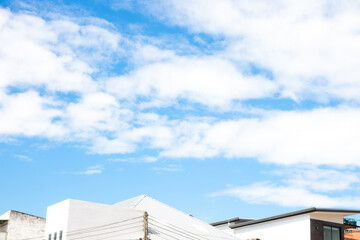 A blue sky with a few clouds and a white house in the background