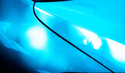 A blue car with a shiny paint job. The paint job is so bright that it almost looks like it's glowing